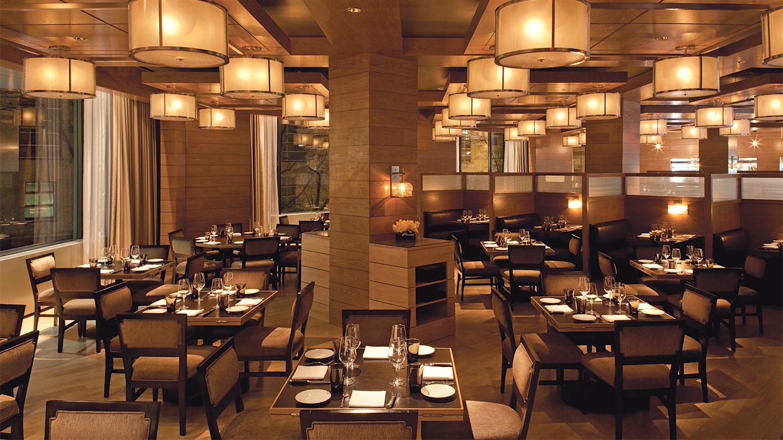 The modern-design dining room at Bourbon Steak D.C., with round light fixtures on the ceiling and wood accents throughout